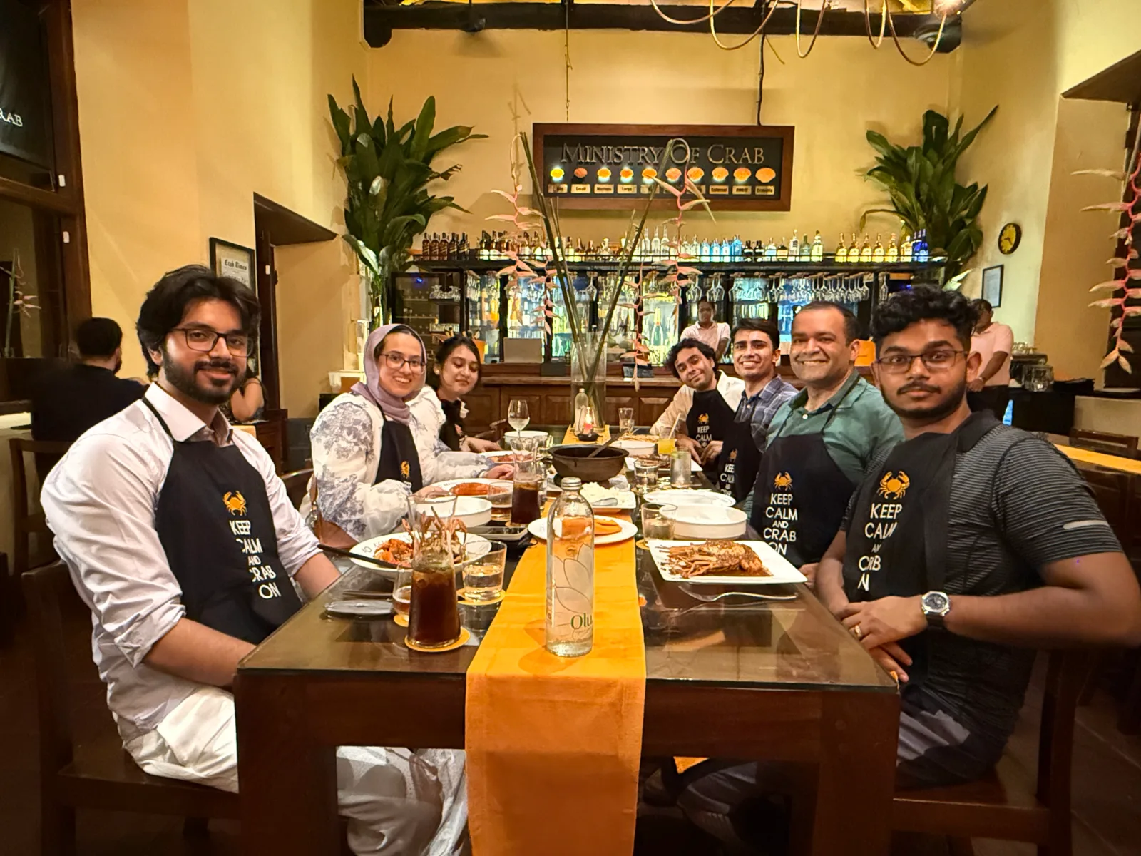 The team at dinner in a restaurant, wearing "Keep calm and crab on" aprons
